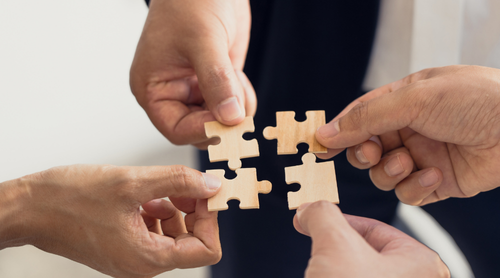 The concept of teamwork and partnership. Businessman's hands putting together puzzle pieces in the office and join together in a jigsaw puzzle team. Charity. Volunteers. Business unity as a team.