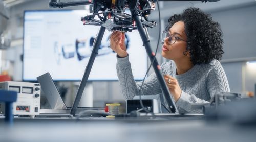 Concentrated Black Female Engineer Writing Code. Developing Software for Modern Drone Control in the Research Center Laboratory. Technological Breakthrough in Flight Industries Concept.